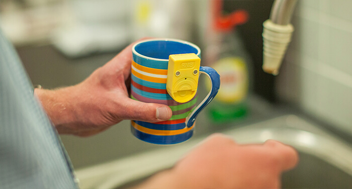 Someone holding a mug with a sensor attached to the side