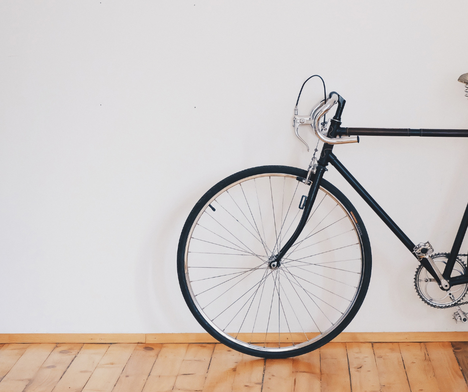 Front wheel and handlebar of a bike leaning on a white wall