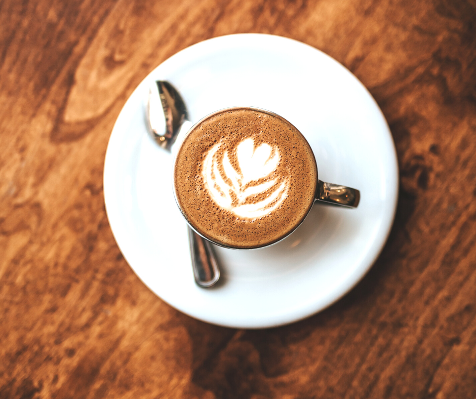 A cup of coffee from above with a cream flower decoration on top.