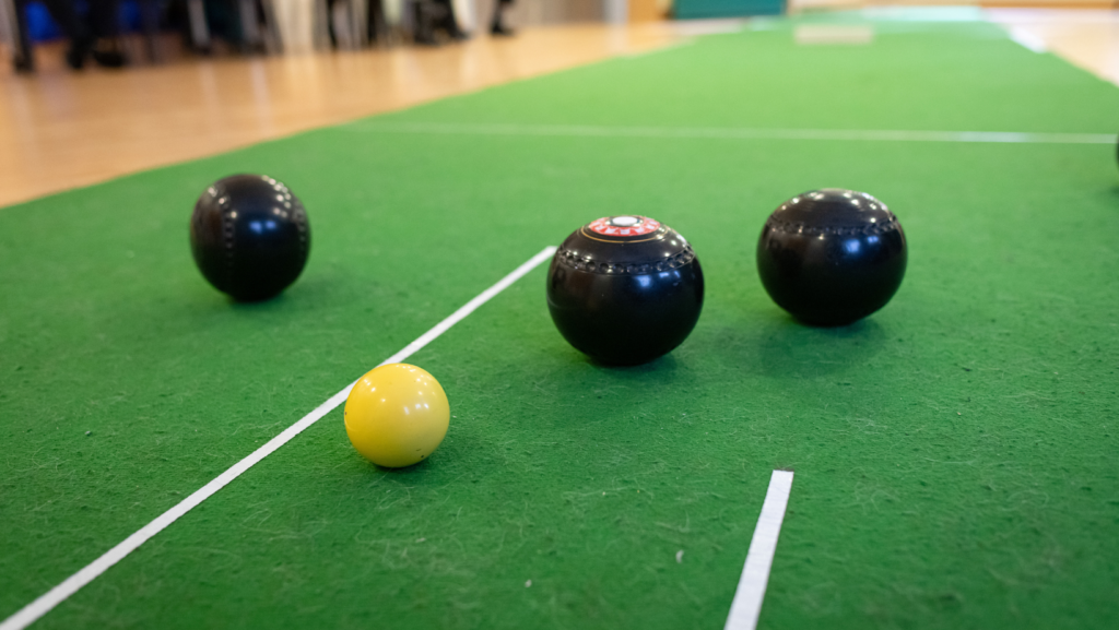 Black and white bowls balls on the green mat inside the activity centre