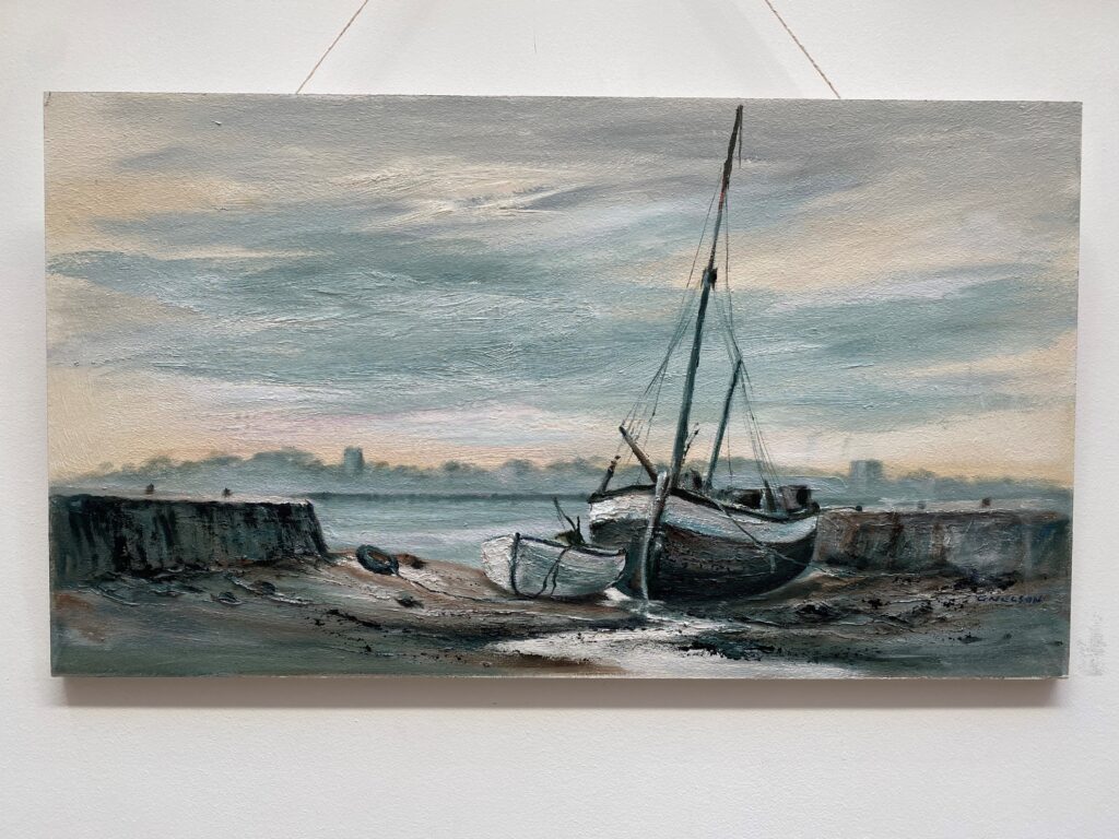 Close up picture of one of the paintings featuring a small grounded boat and row boat on the beach.