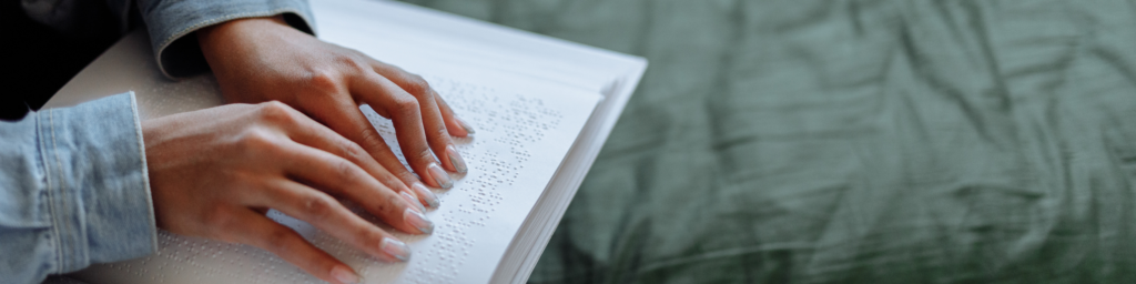 Two hands reading a braille book