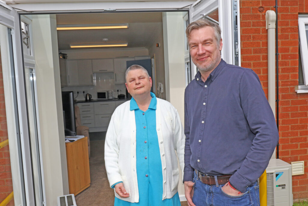 Hammond Court resident Kate Pentney outisde the patio doors of her flat, with Vision Norfolk chief executive Andrew Morter