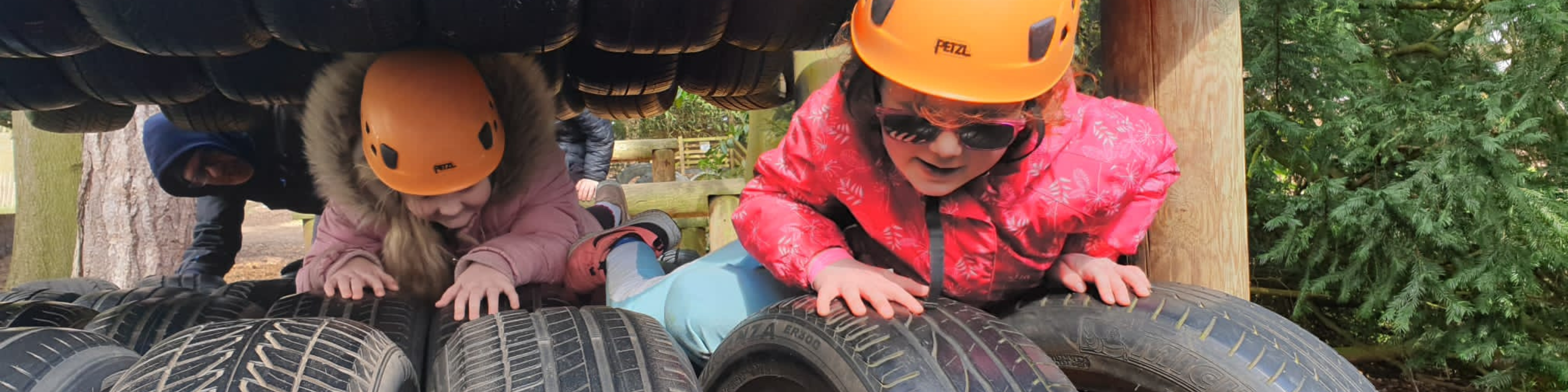 Two young children wearing safety helmets, crawling through an obstacle course.