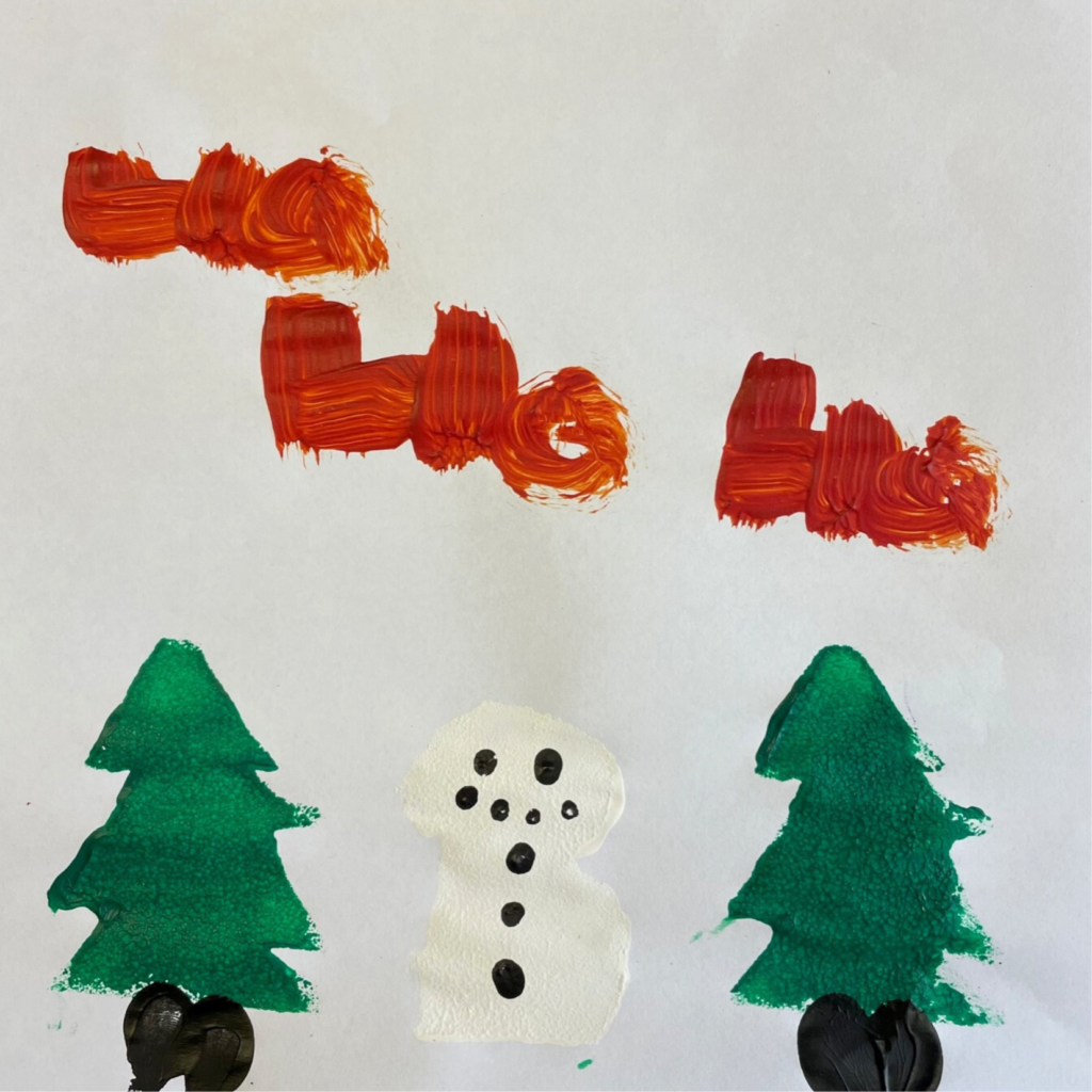 A snowman and two evergreen trees painted on white paper. At the top of the image "ho ho ho" is written in red paint.