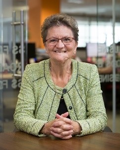 A picture of Vision Norfolk Trustee Jenny Manser. A woman with short brown hair sitting with an office in the background.