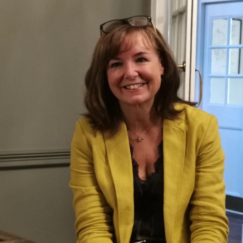Image of Vision Norfolk Trustee Rachael Laurie. A woman in a yellow blazer with mid length brown hair, smiling at the camera.