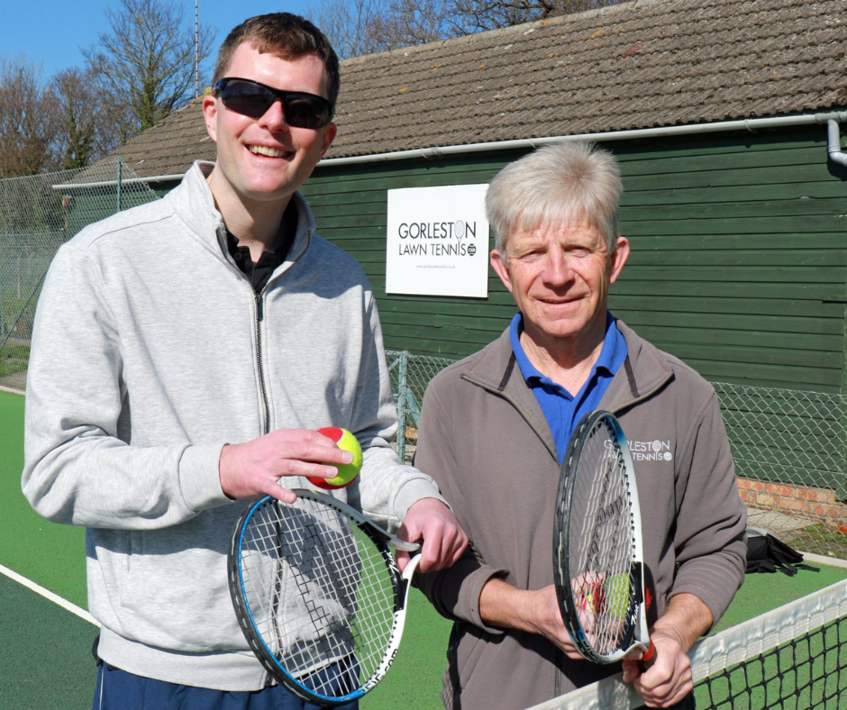 Vision Norfolk Great Yarmouth Hub Coordinator Edward Bates (left) and tennis coach Mike Reynolds standing on a tennis court at Gorleston Tennis Club holding tennis rackets and balls.