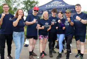 A group of people wearing Vision Norfolk T-shirts who are about to take part in a fundraising event.