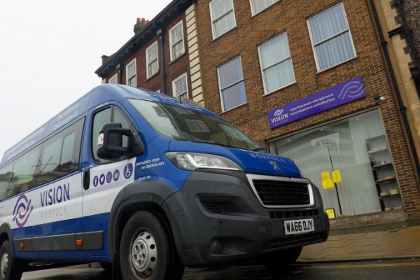 A vision Norfolk minibus parked on the road outside a Vision Norfolk office.