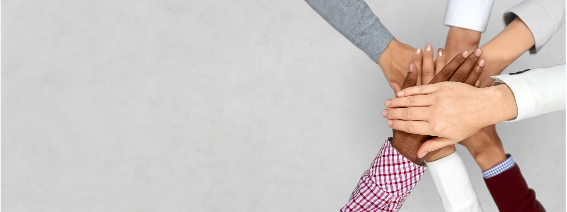 A stylised image of six hands forming a ‘hands-in’ gesture as a symbol of collective motivation and teamwork. The image is shot from above.
