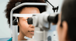 A woman lets an optometrist shine a light in her eyes as part of an eye test.
