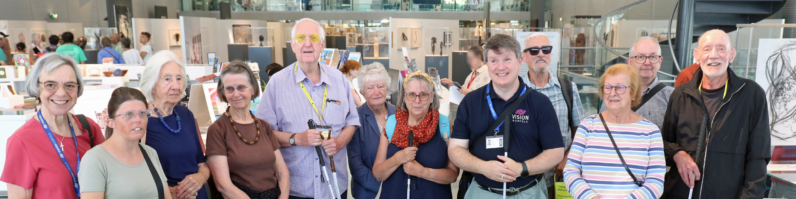 A group of 12 people standing inside the main exhibition room of the Sainsbury Centre in Norwich.