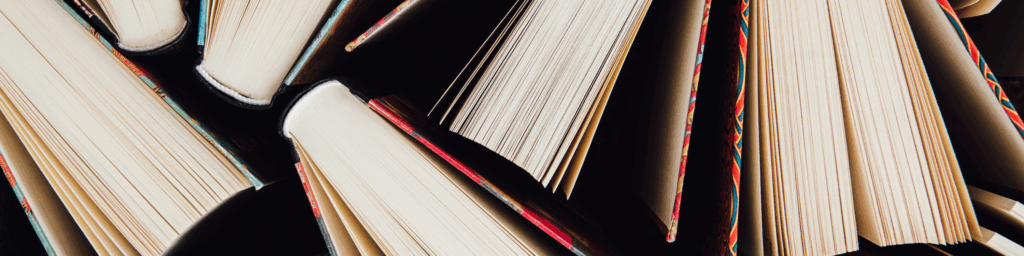 The spines and pages of slightly opened books photographed from above.