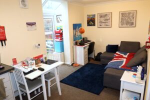 The living room in a flat in Hammond Court with a small table, desk, and sofa with a union flag blanket.