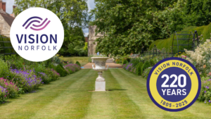 A photo of a garden urn siting between two rows of plants in The Bishop's Garden in Norwich. At the bottom is the text "Summer Garden Party, Sunday 26th July, 1pm-4:30pm, Bishop's Garden, Norwich. In the top left corner is the Vision Norfolk Logo and in the bottom right corner is the 220th anniversary logo.