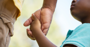 A small child holding hands with an adult.